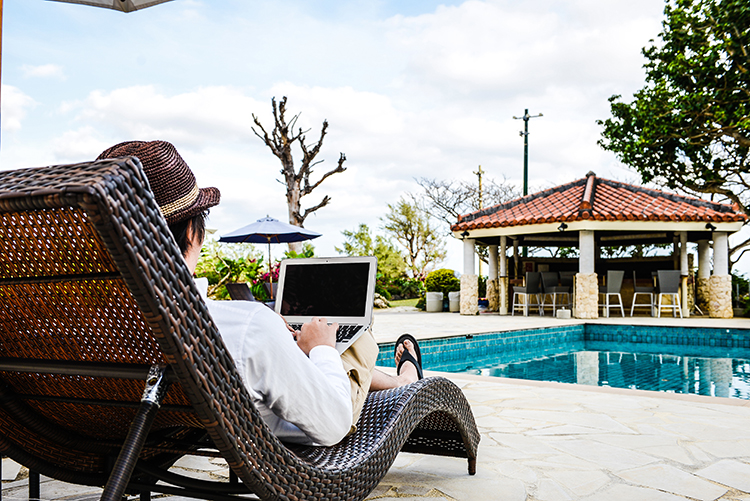 プールサイドでパソコンを操作する男性